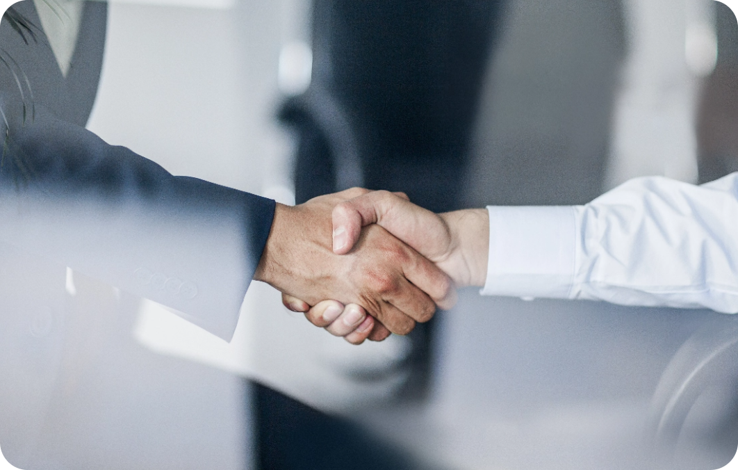 Two office workers shaking hands after lease management meeting.